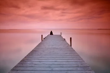 Deurstickers Pier Eenzame persoon zittend op de pier