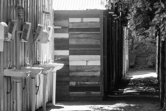 Abstract black and white image row of wooden cottage at countryside with row of whit ceramic sink in foreground.