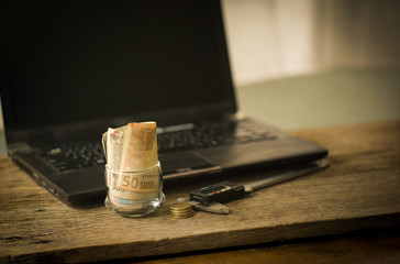 Business and finance concept, Euro banknote and coins in the glass setting near the laptop, Digital Vernier Calipe, put on brown natural texture wooden table.