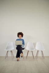 Fototapeta premium African American businesswoman sitting in waiting room and using laptop