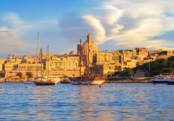 Fototapeta premium Beautiful travel scene with a red motor boat on the harbor in Valletta Capital, Malta