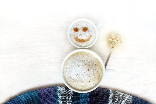 coffee snowman with a smile/ two cup with a frothy cappuccino are decorated with cinnamon and cookies top view