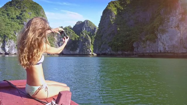 Camera Shows Girl in Bikini Making Selfie in Calm Bay by Rocks
