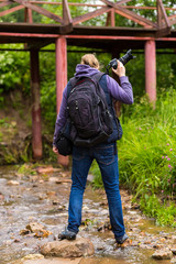 traveler photographer river bank covered with grass path to the iron bridge