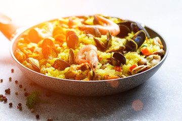 Traditional spanish seafood paella in pan rice, peas, shrimps, mussels, squid on light grey concrete background. Top view, copyspace