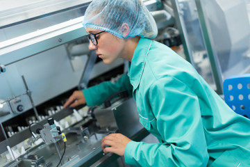 worker operates the machine at the enterprise, clean room with stainless steel hardware