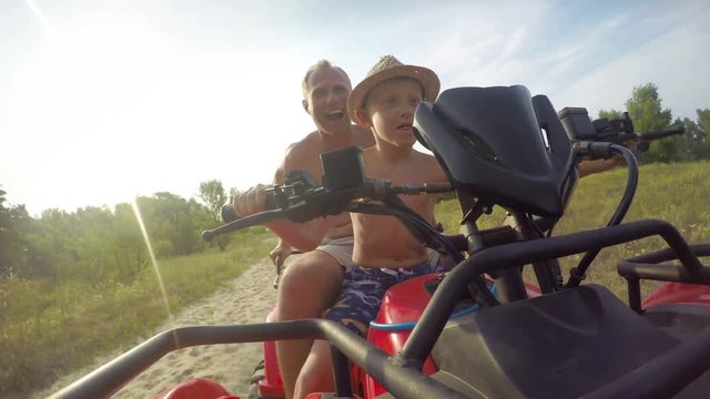 4K footage of father and son riding an ATV in terrain on a sunny warm day