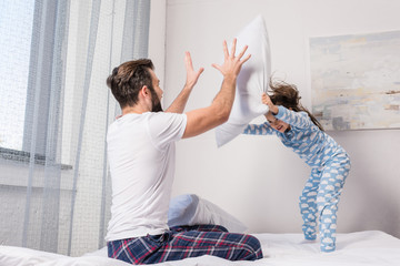 father and daughter playing pillow fight