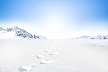 Fototapeta na wymiar Winter Background of foreground of road covered with snow and ice. In the background, the arctic landscape of the mountains with the beautiful blue sky.