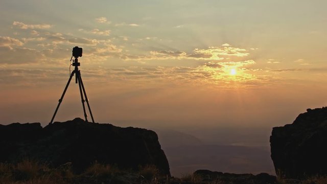 Professional camera silhouette on cliff running time lapse at sunrise