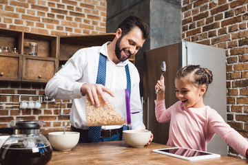 father making cereal breakfast for daughter