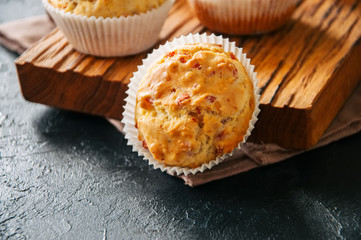 Homemade muffins with bacon and cheese on a black slate background. Healthy snack or breakfast meal.