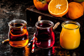 Fresh fruit and juices variety. Oranges, pomegranate and apples. Dark rusty background, with wooden tray, copy space