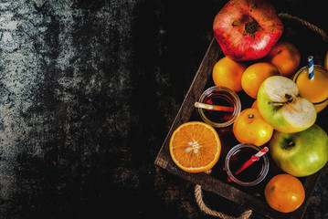 Fresh fruit and juices variety. Oranges, pomegranate and apples. Dark rusty background, with wooden tray, copy space close top view