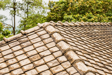 square stone tile on the roof of a Thai cottage with rounded edges on a blurred background of trees