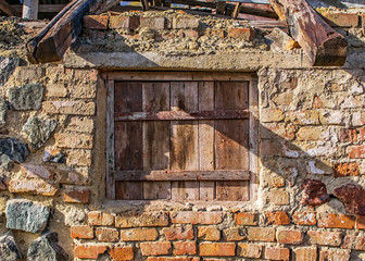 Old brick wall with boarded up with wooden boards window. Wall of an abandoned ruined building