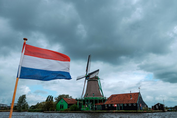 Windmühlen und holländische Fahne vor bewölktem Himmel