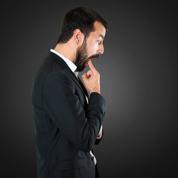 Handsome businessman making vomiting gesture on black background