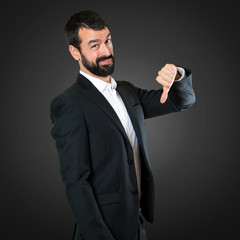 Handsome businessman making bad signal on black background