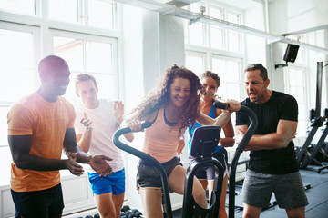 People cheering on their friend riding a gym stationary bike