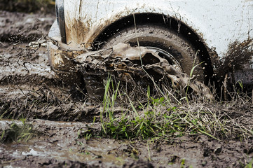 Fototapeta na wymiar Car wheel on a dirt road. Vehicle tire closeup. Mud splashing off. Outdoors, adventures and travel suv.