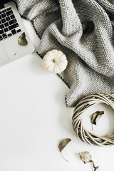 Flat lay composition. Workspace with laptop, white pumpkins, grey plaid and wreath frame. Top view autumn or winter concept.
