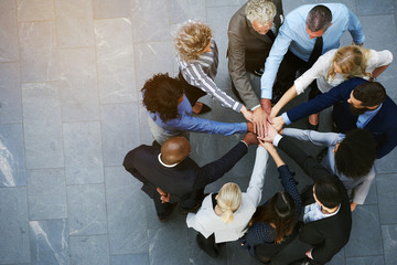 United businesspeople standing in a huddle with their hands together - Powered by Adobe