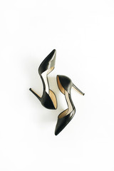 Obraz premium Black female high heels on white background. Flat lay, top view.