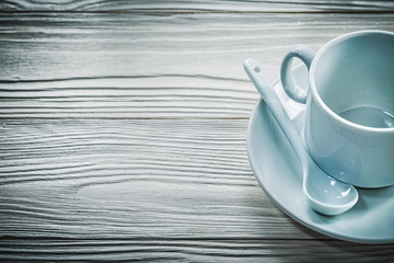 White cup saucer teaspoon on wooden board