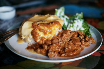 Thai Food Panaeng Curry with Pork and omelet on cooked rice in white plate
