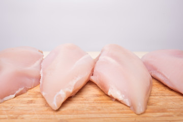 Fresh chicken fillet on a bamboo cutting board on a light background
