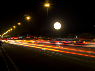 Fototapeta na wymiar Motion light of traffic with big full moon at night