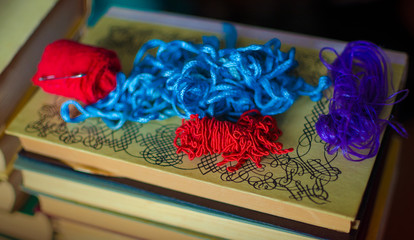 Some red, blue and purple antique ropes laying on a stack of old books.