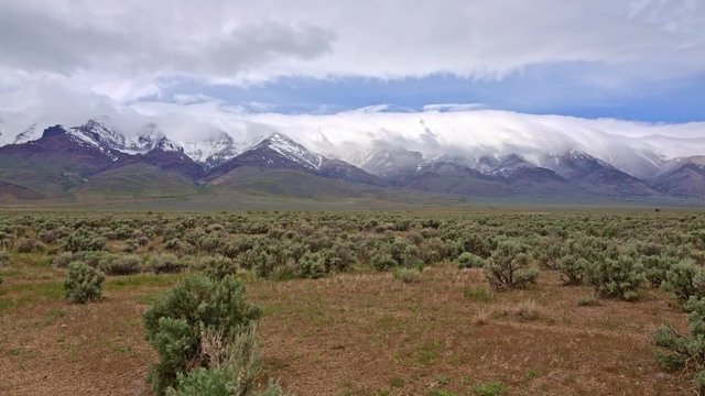 Snowcapped desert mountains and clouds spring Steens Mountain from Alvord Desert and sagebrush