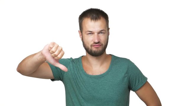 slow motion portrait of adult guy in shirt with short dark hair shaking head negatively showing dislike sign thumb down over white background closeup. Concept of emotions