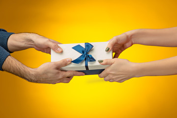 The closeup picture of man and woman's hands with gift box