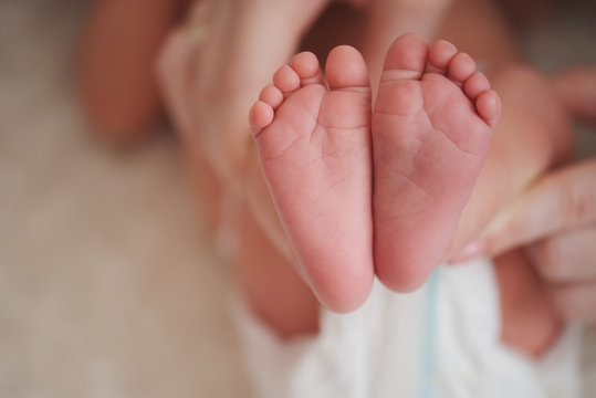 mother holds little foot of newborn baby