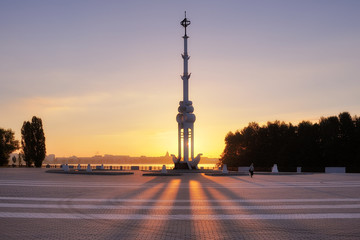 Fototapeta na wymiar Sunrise at the Admiralty Square. The first solar rays penetrate the rostral column in the Admiralty Square in the summer. Warm summer light at dawn. A lonely man walks in the morning at dawn.