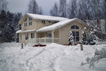 Suburban house covered with snow in winter evening  