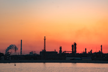 川辺の工場が夕日に写るオレンジ色の空