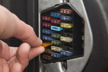 The auto mechanic inserts or pulls out the fuse from the box with the fuses of the car.