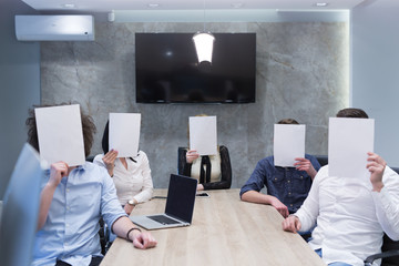 startup business team holding a white paper over face
