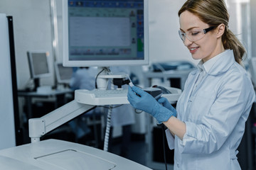Well equipped laboratory. Positive nice cheerful woman smiling and wearing protective glasses while...