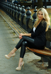 Fashion glamour model posing on the bench at the autumn park.