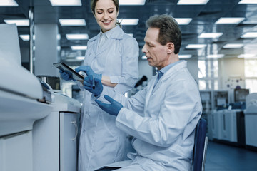 Obraz premium Scientific research. Smart handsome nice man sitting on the chair in the lab and holding a test tube while carrying out a scientific research