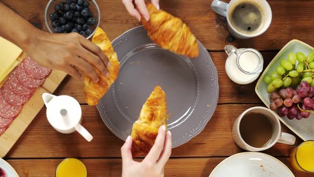 hands taking croissants from table with food