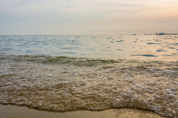 Artistic photo. Close-up on a wave withdrawing on the sand of a beach in the sunset