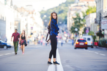 Beauty Glamor young Woman looking with interest goes. Long hair. Fashionable lady with a beautiful hairdo, makeup. against the background of new buildings in the city. fashionable dress. Copy space