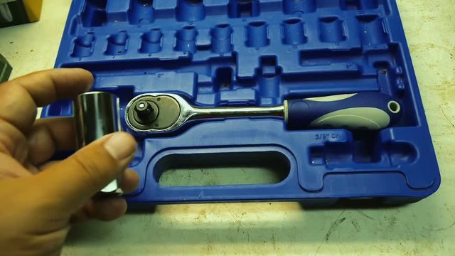 Male hand is trying to find right place for large socket wrench part in plastic toolbox container. Filmed in slow motion hd.