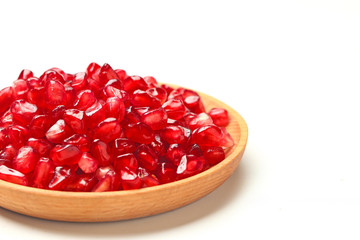 pomegranate seeds in wooden plate isolated on white background